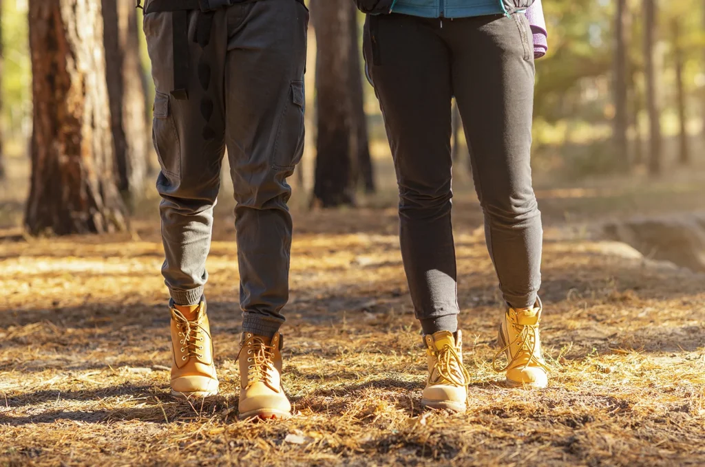 legs of two hikers crossing forest