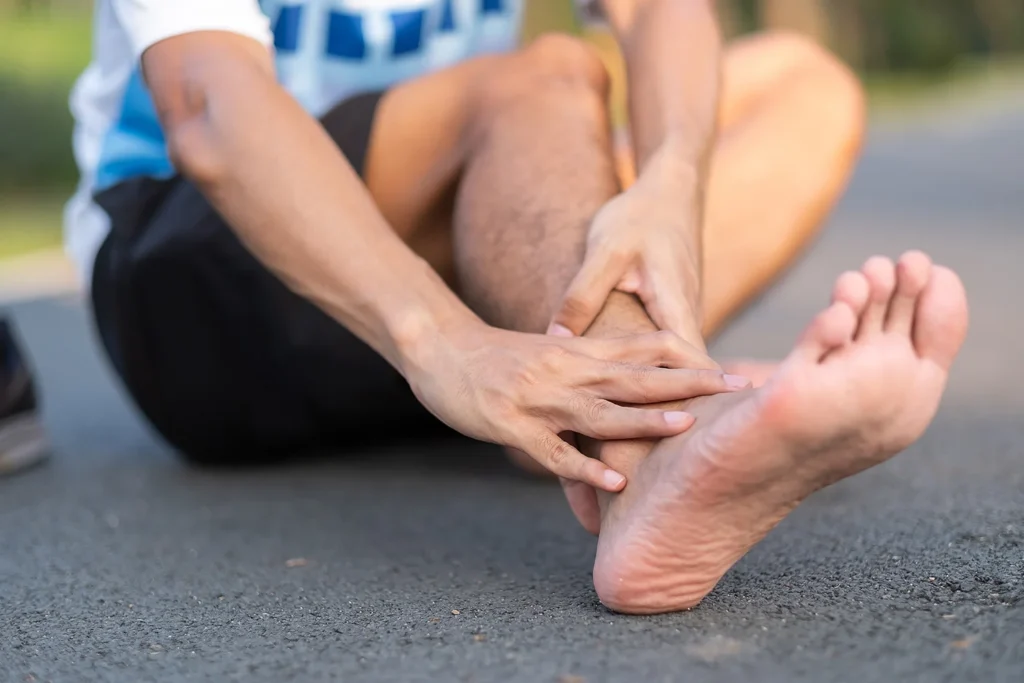 man holding ankle in pain sitting